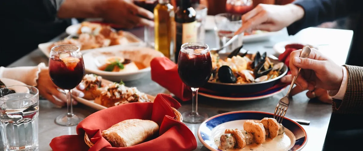 Delicious spread of authentic Spanish tapa spread across a table served with two drinks as customers dig in.