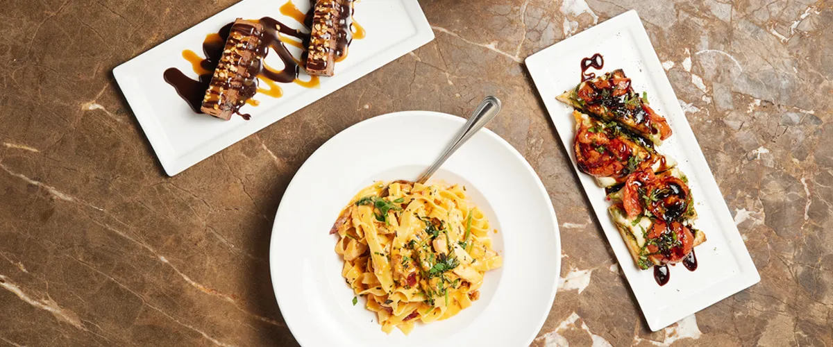 A delicious spread of Italian food from Trezo Mare restaurant laid out across the table including an appetizer, pasta, and a dessert.