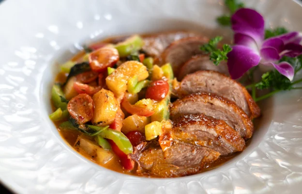 Delicious Thai food available at Aqua Penny’s served with meat, vegetables, and decor in a small bowl.