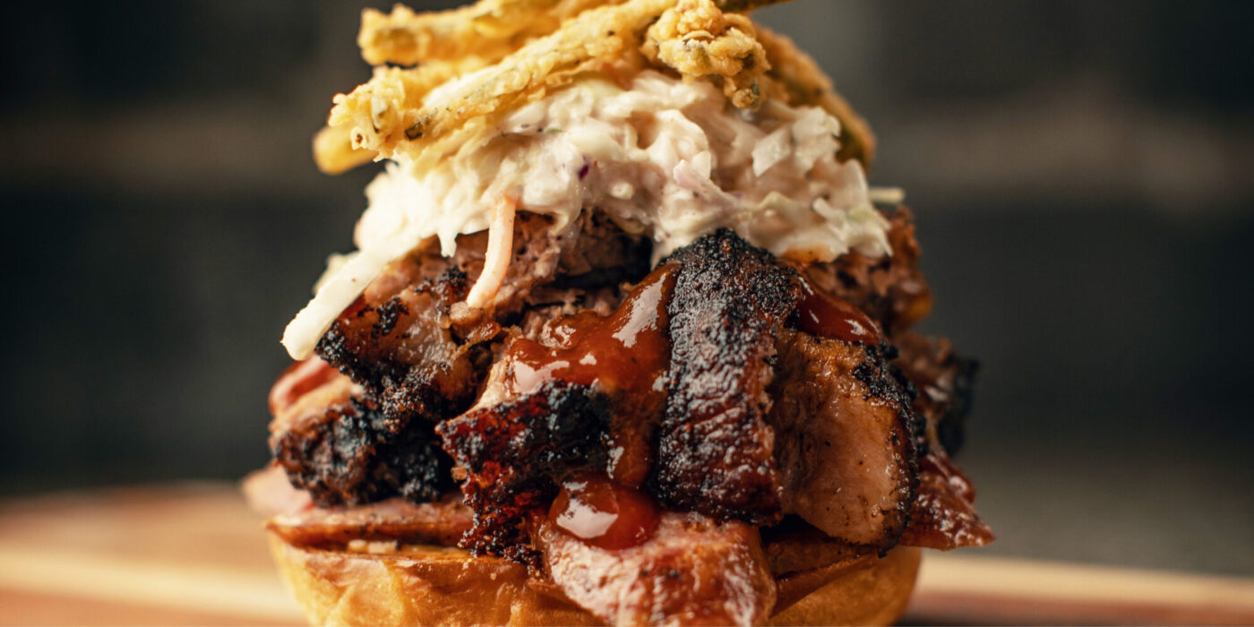 Delicious pulled pork on a bun with coleslaw and deep fried onions both stacked on top.