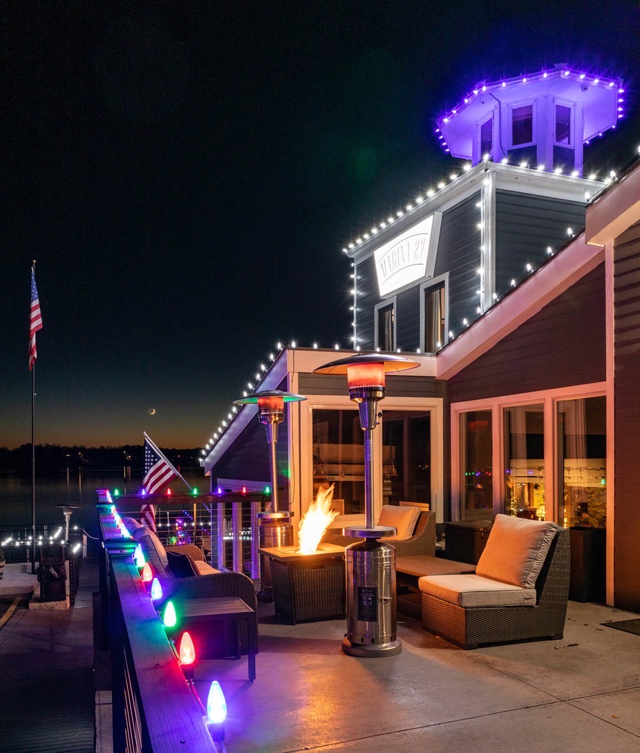 The exterior view of the Marina 27 restaurant in Kansas City painted blue with red umbrellas and flower decor