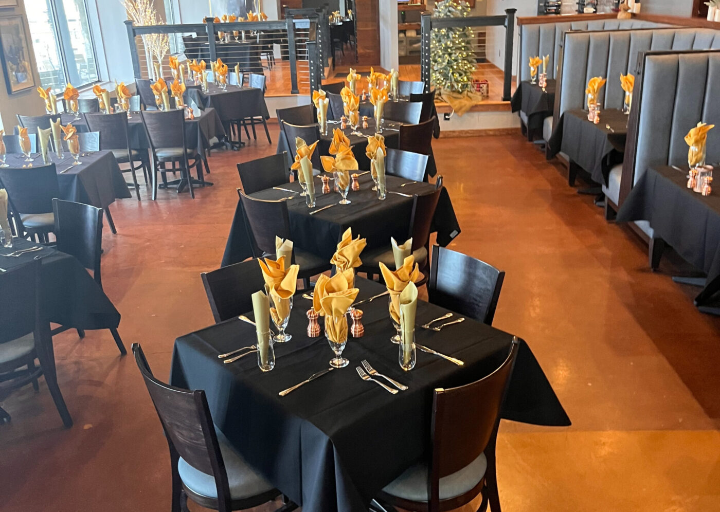 Interior of Marina 27 Steak & Seafood with modern seating and multiple tables covered with black cloths and black seats seated near them.