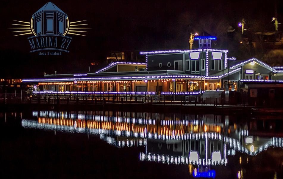 The outside view of Marina 27 Steak & Seafood during Christmas with festive lights strewn about the exterior.