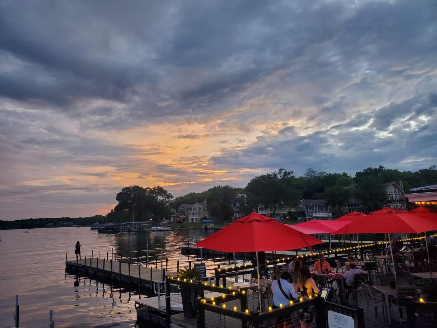 The outdoor view of Marina 27 Steak & Seafood with the sunsetting in the background across the quiet water.