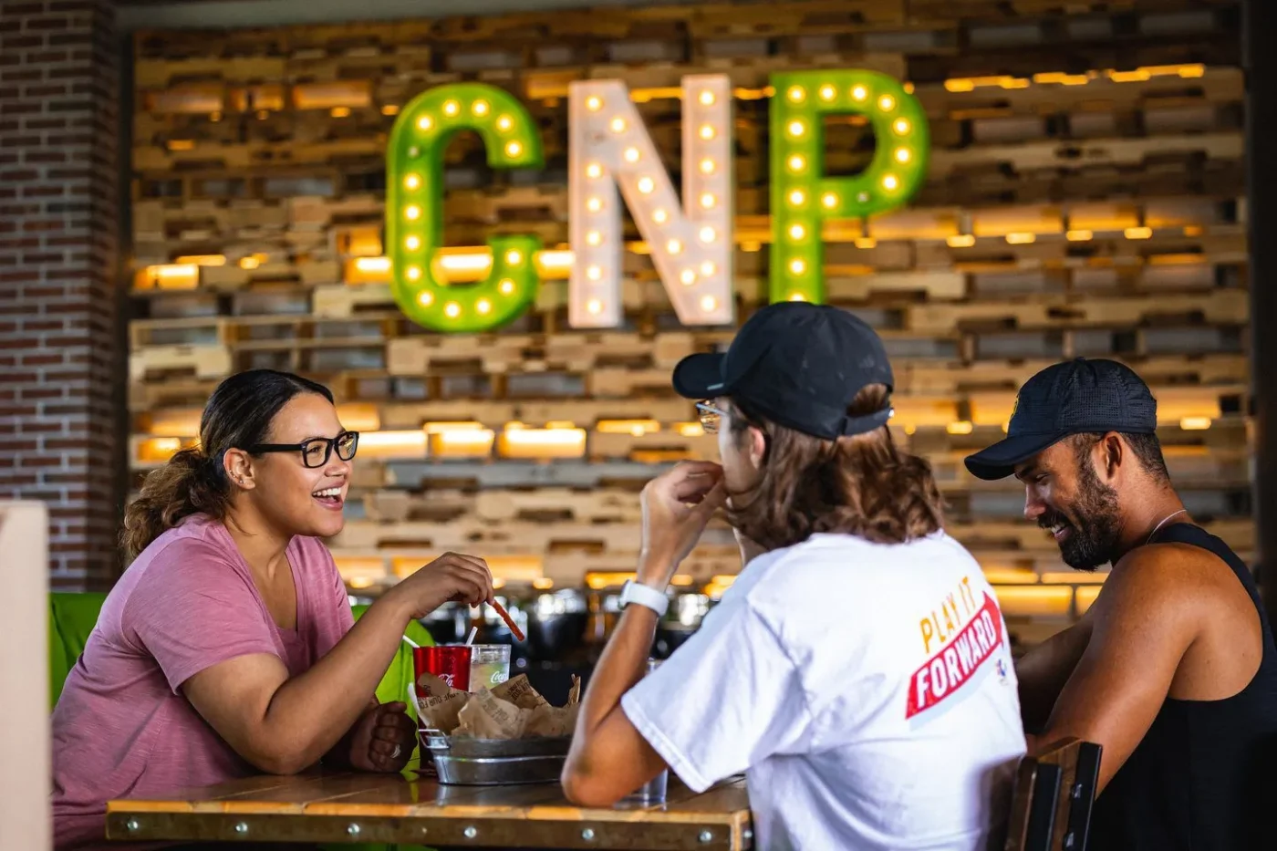 Three customers enjoy some delicious appetizers while smiling and laughing at the Chicken-N-Pickle.