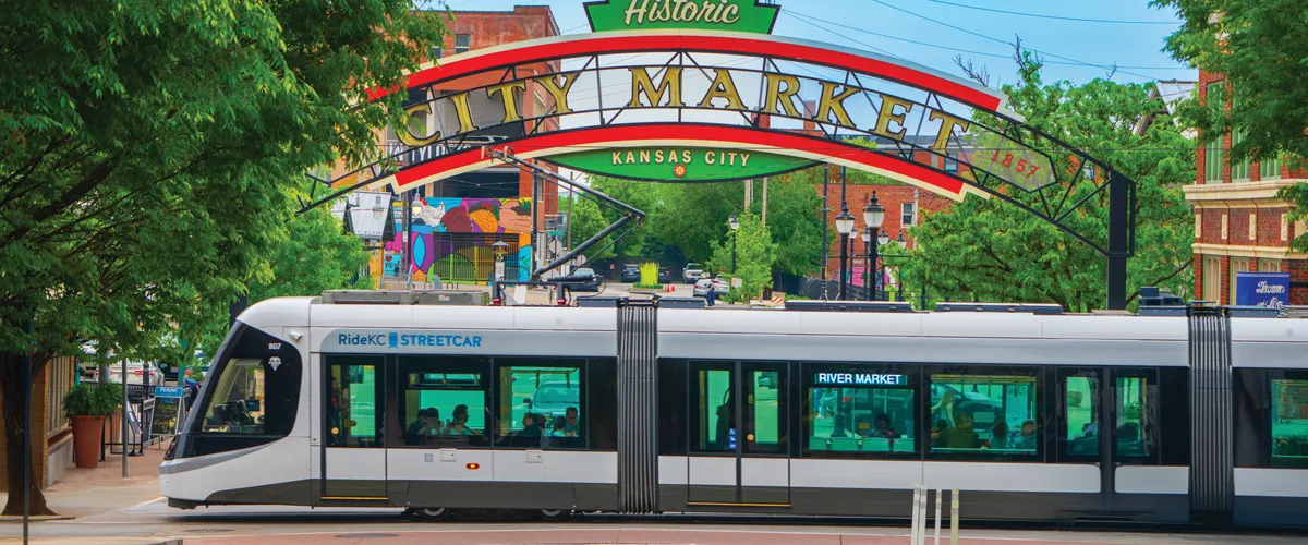 The Kansas City RideKC Streetcar passes through an intersection underneath the Historic City Market sign.