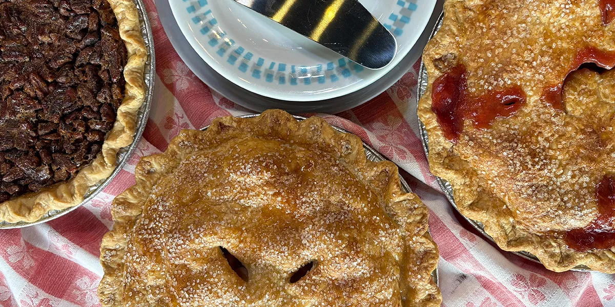 Table full of different kinds of pies at the Upper Crust including Apple and Cherry pie.