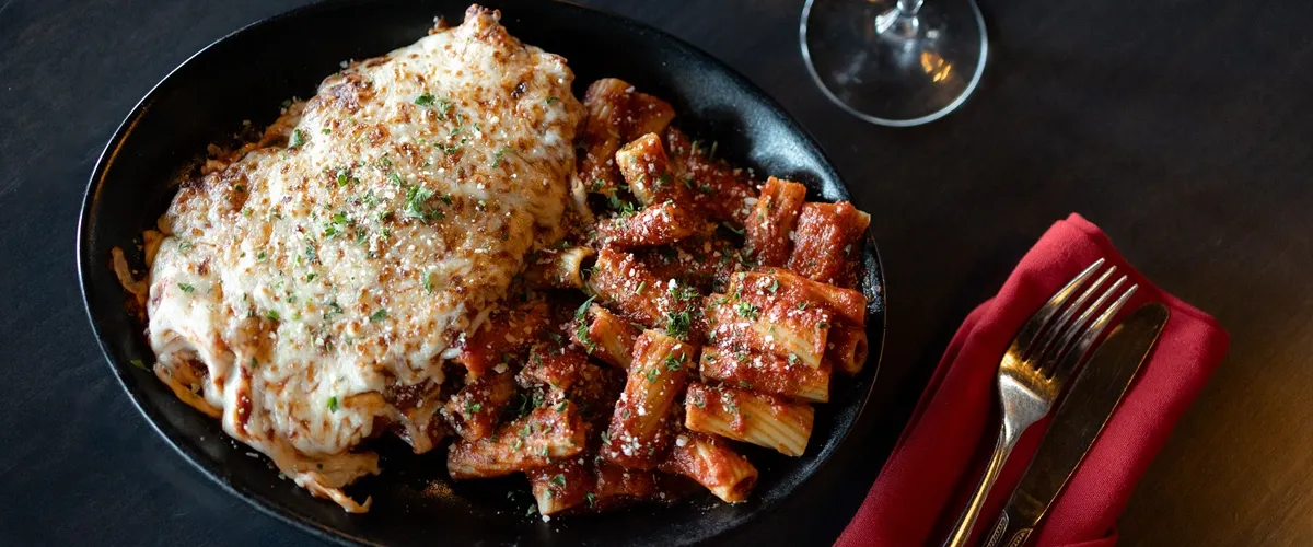 The classic chicken parmesan featuring fried chicken breast with cheese melted on top served with rigatoni pasta.