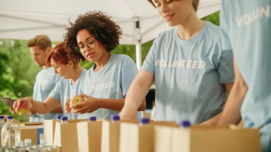KC Restaurant Week Volunteers in light blue shirts stock bags full of water and fruit.